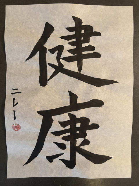 vertically written japanese calligraphy in black ink on white paper, with a signature and red seal on the left side